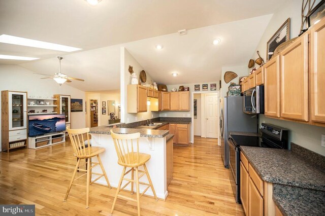 kitchen featuring light wood-style flooring, a peninsula, stainless steel microwave, black range with electric cooktop, and vaulted ceiling