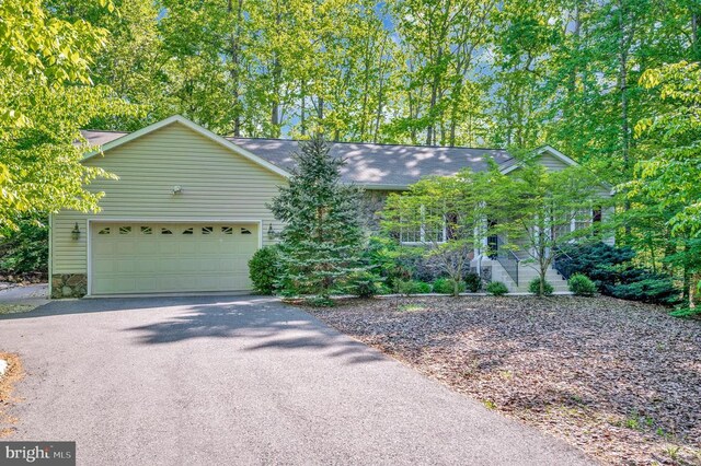 single story home featuring a garage, driveway, and stone siding
