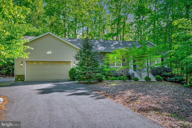 ranch-style house with a garage and aphalt driveway