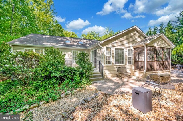 back of property with a sunroom and a patio area