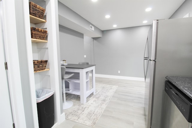 kitchen featuring dark stone countertops, stainless steel appliances, and light wood-type flooring