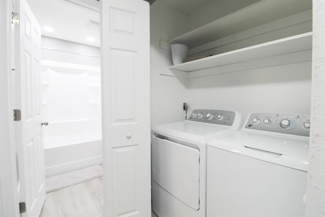 clothes washing area with light hardwood / wood-style floors and independent washer and dryer