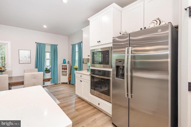 kitchen featuring light wood-type flooring, stainless steel appliances, light countertops, and white cabinetry