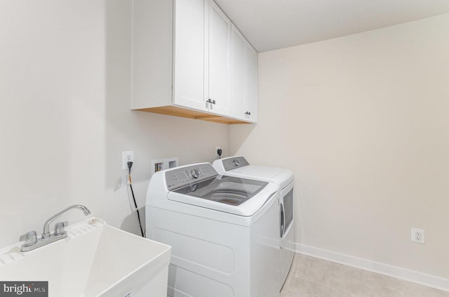 laundry room featuring washing machine and clothes dryer, baseboards, a sink, and cabinet space