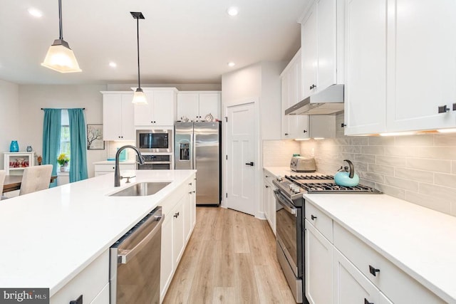 kitchen featuring white cabinets, recessed lighting, under cabinet range hood, a sink, and appliances with stainless steel finishes