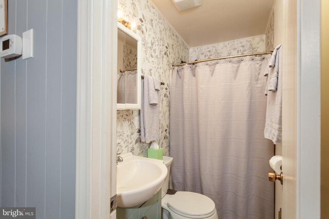 bathroom with walk in shower, vanity, and toilet