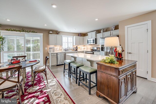 kitchen with sink, a breakfast bar, stainless steel appliances, a center island, and white cabinets