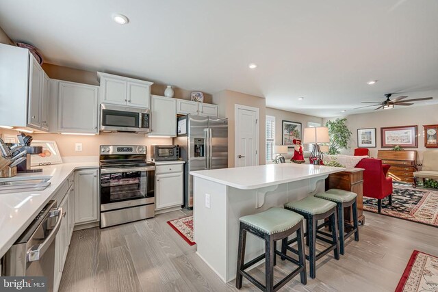 kitchen featuring a kitchen island, appliances with stainless steel finishes, sink, a breakfast bar area, and white cabinets