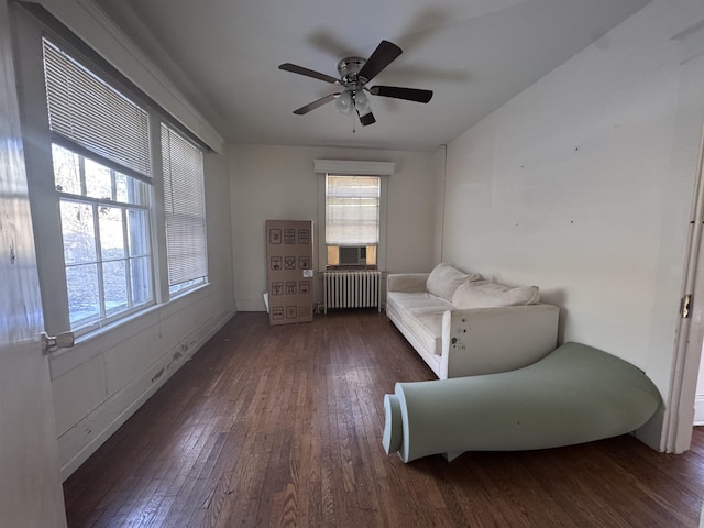 living area with dark wood-type flooring, ceiling fan, and radiator