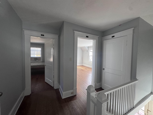 hallway with dark hardwood / wood-style floors and a textured ceiling