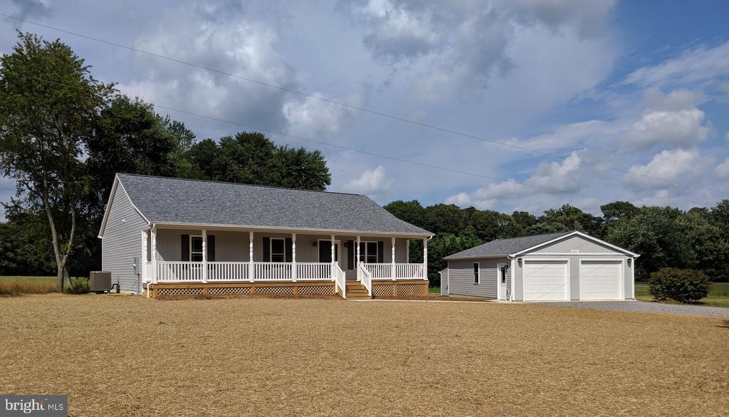 view of front of home with a porch, a garage, central AC unit, and an outdoor structure