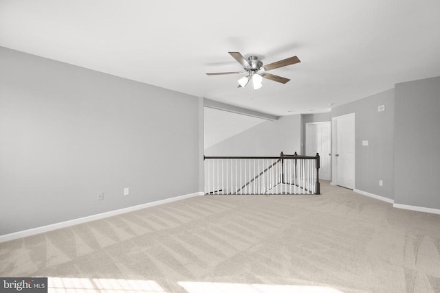 carpeted spare room with baseboards and a ceiling fan