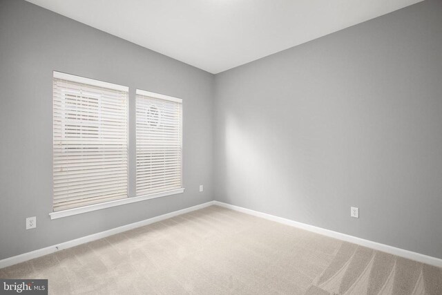 unfurnished room featuring baseboards and light carpet