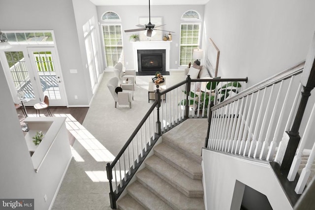 stairs featuring a fireplace with flush hearth, baseboards, and a ceiling fan