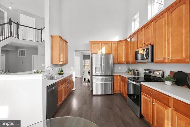 kitchen featuring a healthy amount of sunlight, visible vents, a high ceiling, a sink, and stainless steel appliances