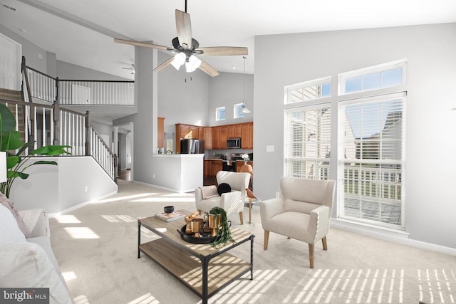 living room with stairway, a ceiling fan, baseboards, and light carpet