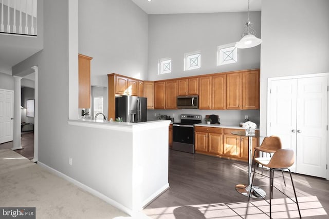 kitchen with brown cabinetry, baseboards, light countertops, appliances with stainless steel finishes, and decorative light fixtures