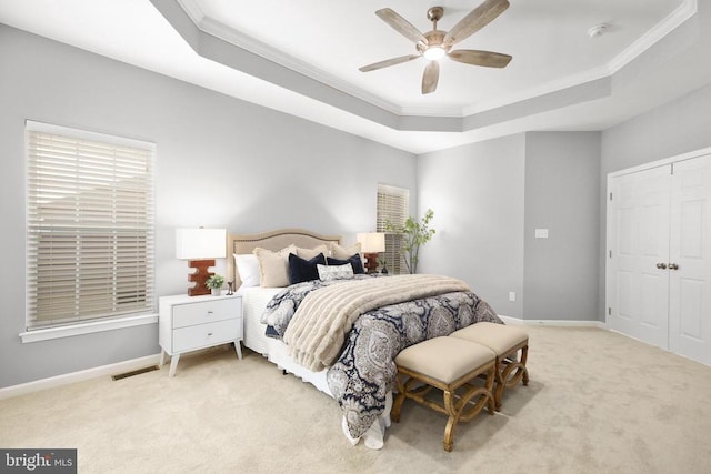 bedroom featuring carpet, visible vents, baseboards, a tray ceiling, and crown molding