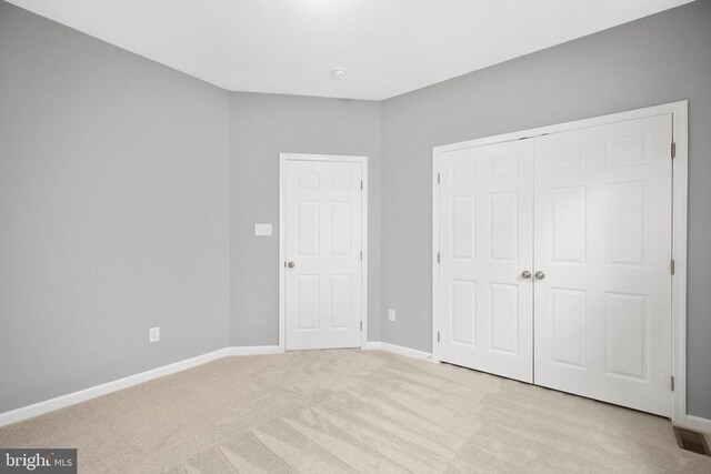 unfurnished bedroom featuring a closet, visible vents, light colored carpet, and baseboards