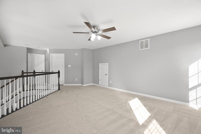 carpeted spare room with visible vents, a ceiling fan, and baseboards