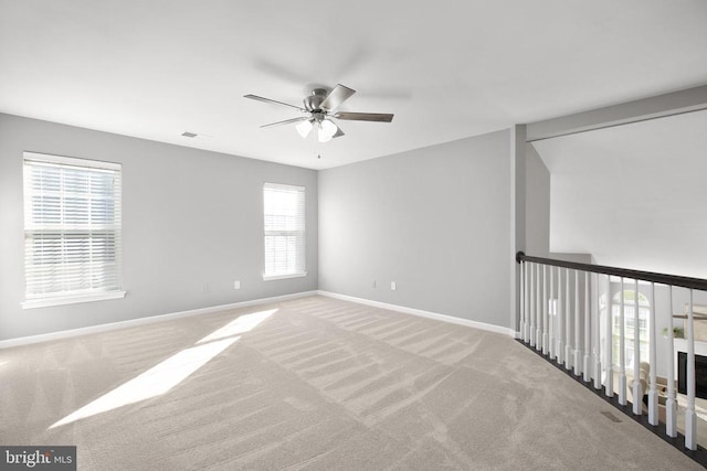 spare room featuring baseboards, carpet floors, visible vents, and a ceiling fan