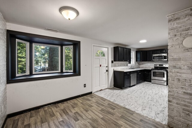 kitchen with stainless steel appliances, tasteful backsplash, sink, and hardwood / wood-style floors