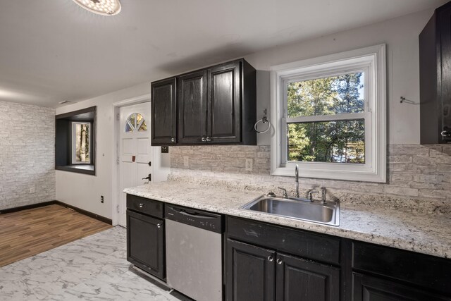 kitchen featuring tasteful backsplash, dishwasher, light stone countertops, and sink