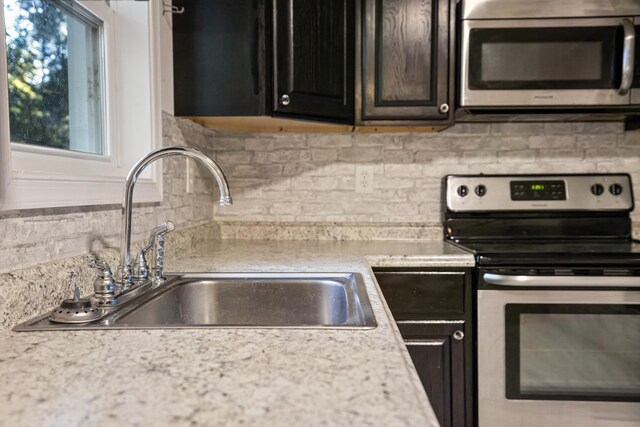 kitchen featuring tasteful backsplash, sink, stainless steel appliances, and light stone countertops