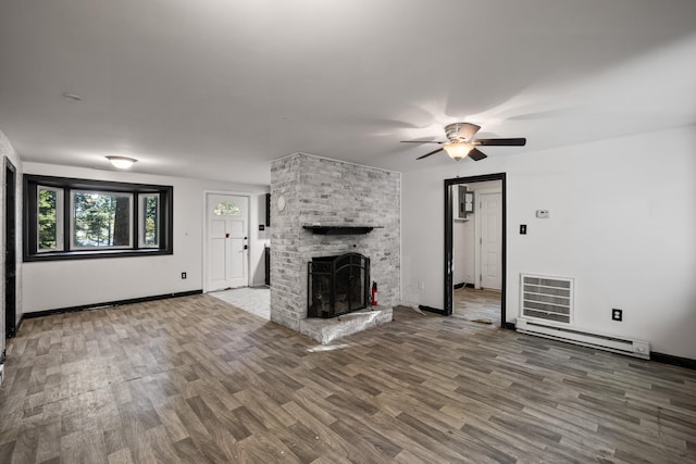 unfurnished living room featuring wood-type flooring, ceiling fan, a fireplace, and baseboard heating