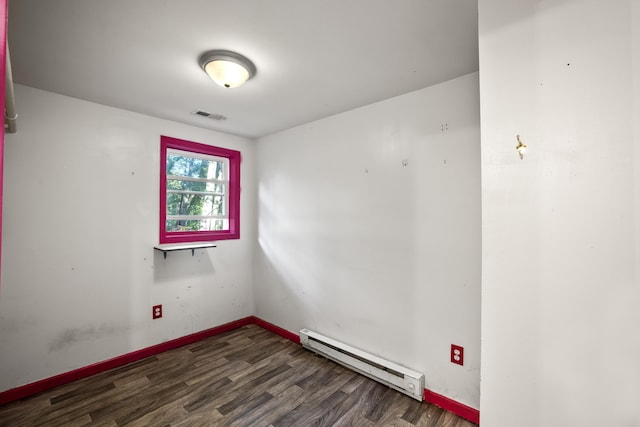 spare room featuring a baseboard heating unit and dark hardwood / wood-style floors