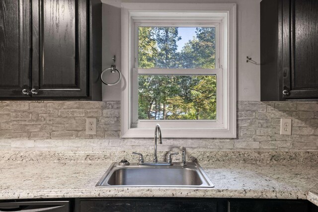 kitchen featuring dishwasher, light stone countertops, sink, and backsplash