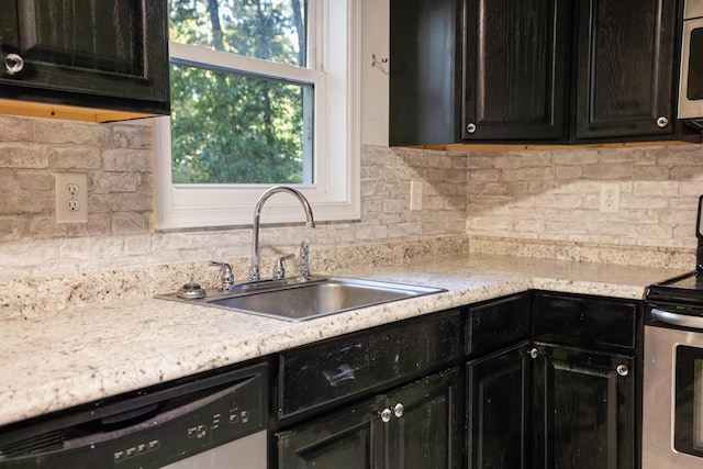 kitchen featuring light stone counters, stainless steel appliances, sink, and backsplash