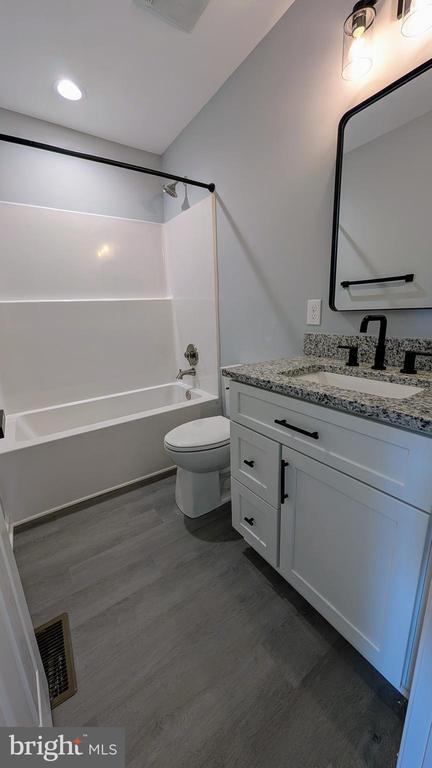 full bathroom featuring vanity, hardwood / wood-style flooring, shower / washtub combination, and toilet