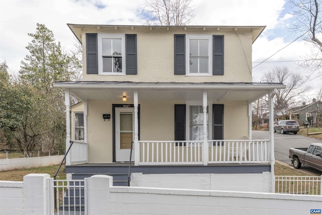 view of front of home featuring stucco siding, covered porch, a fenced front yard, and a gate