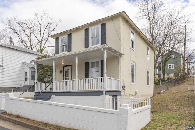 view of front of house with stucco siding, covered porch, and fence