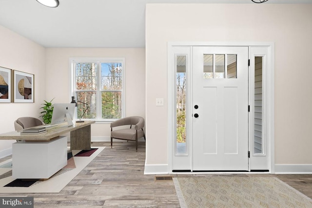 foyer featuring light wood-type flooring, visible vents, and baseboards