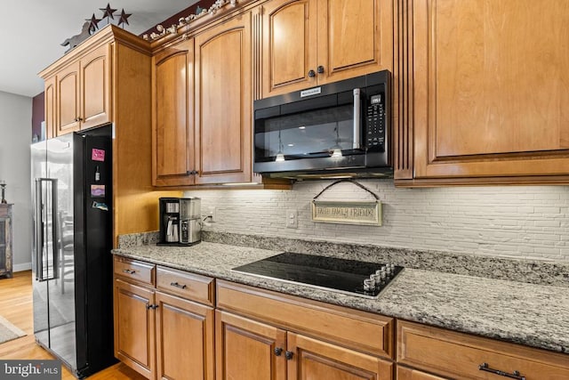 kitchen with light stone countertops, high end fridge, black electric cooktop, and decorative backsplash