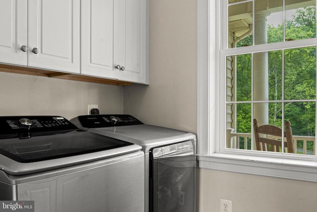 clothes washing area with cabinets and separate washer and dryer