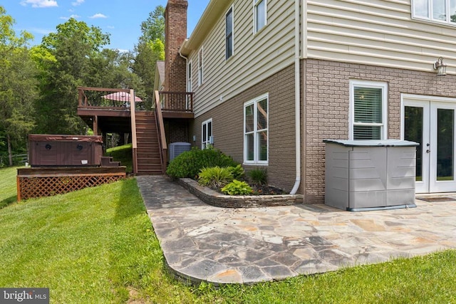 view of home's exterior featuring a lawn, a deck, a patio, a hot tub, and french doors