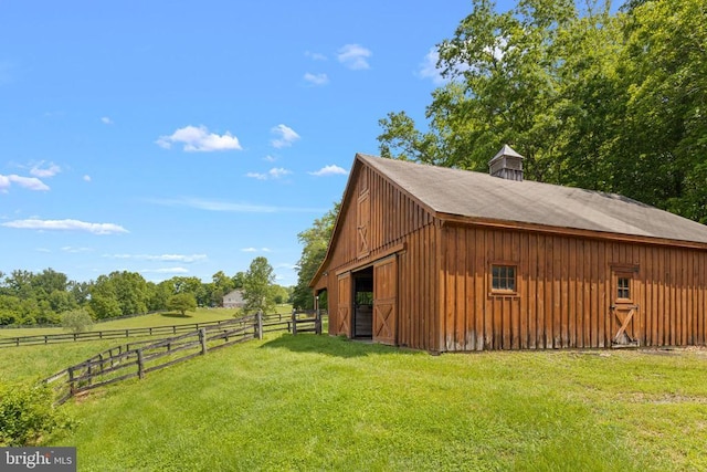 view of outbuilding featuring a rural view and a lawn