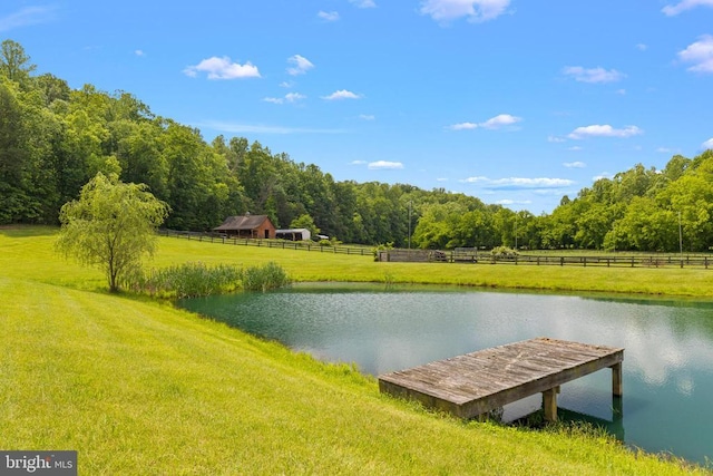 view of dock featuring a water view, a rural view, and a lawn