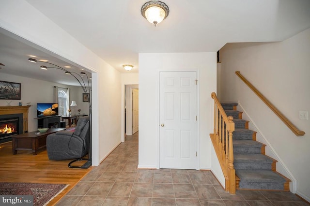 stairway featuring tile patterned floors, a glass covered fireplace, and baseboards