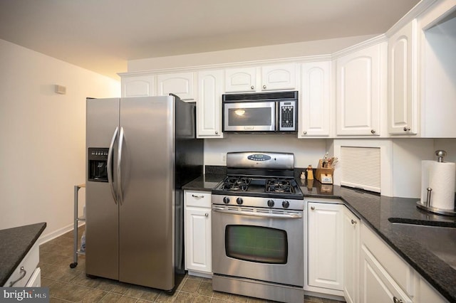 kitchen featuring dark stone countertops, white cabinetry, and stainless steel appliances
