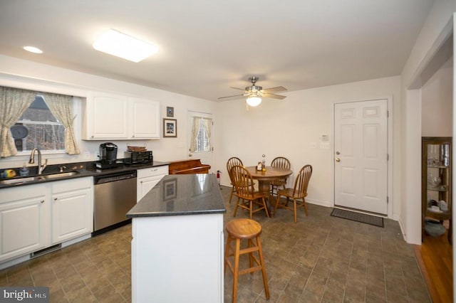 kitchen with visible vents, a kitchen island, stainless steel dishwasher, white cabinets, and a sink