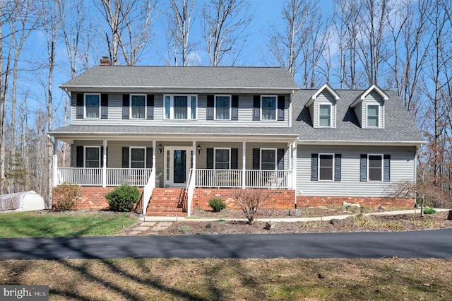 colonial-style house with a porch and roof with shingles
