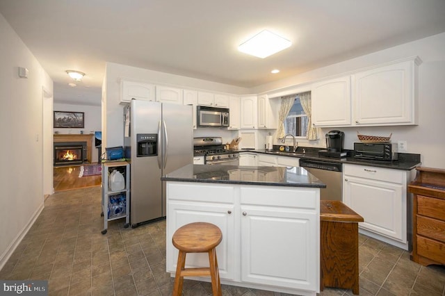 kitchen with a kitchen island, white cabinetry, stainless steel appliances, and a sink