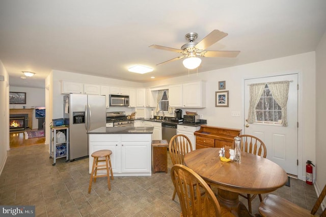 kitchen with a sink, dark countertops, appliances with stainless steel finishes, and white cabinetry