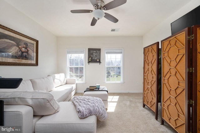 living room featuring visible vents, light carpet, baseboards, and ceiling fan