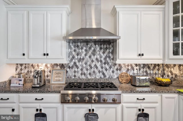 kitchen with stainless steel gas cooktop, white cabinetry, and wall chimney range hood