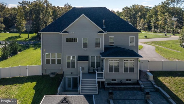 back of property with a lawn, stairs, a fenced backyard, and a gate